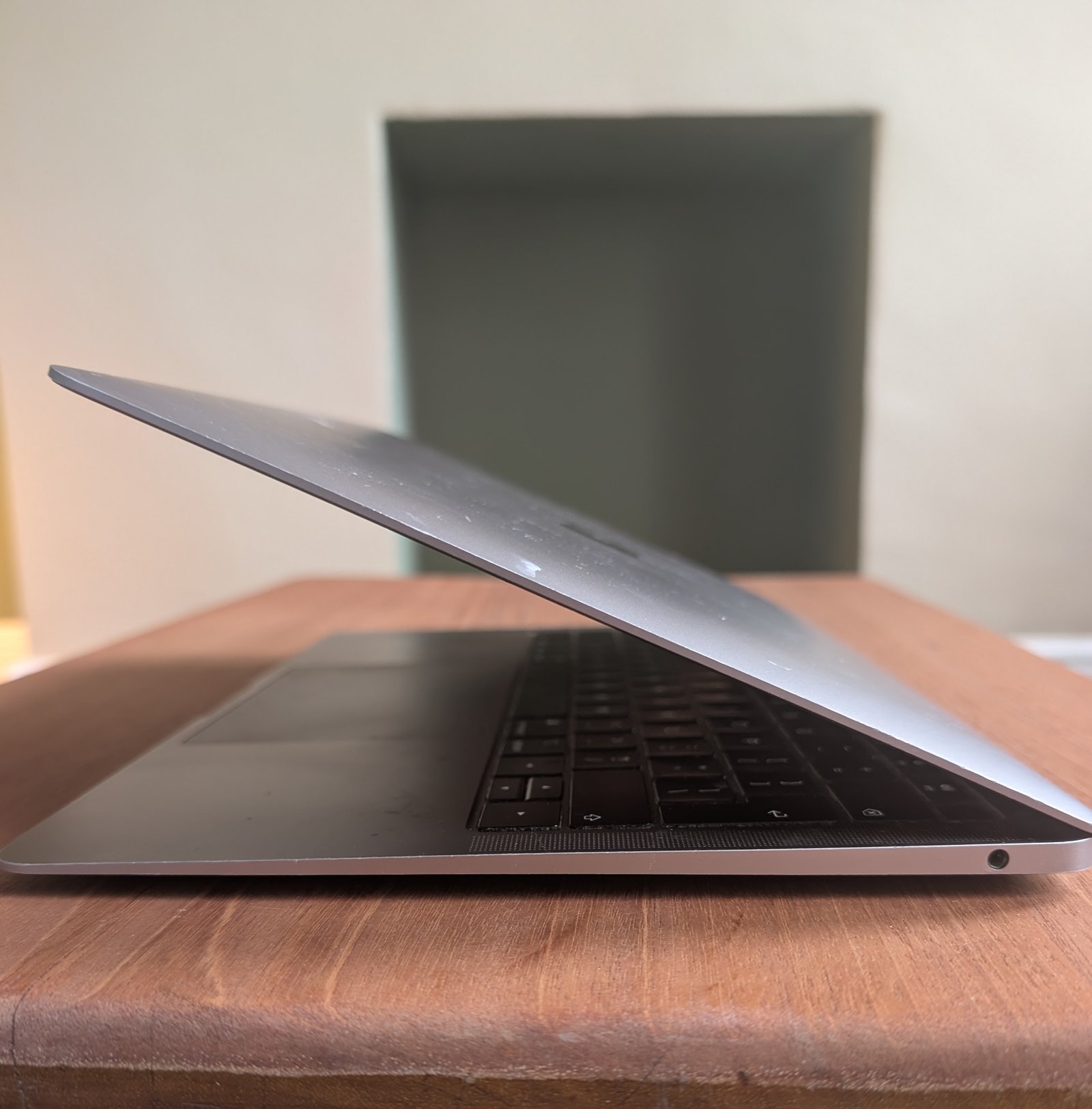 A laptop, slightly open, on a wooden table